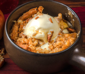Apple Crisp A La Mode. Bowl of hot apple crisp with scoop of ice creams and nuts on top.