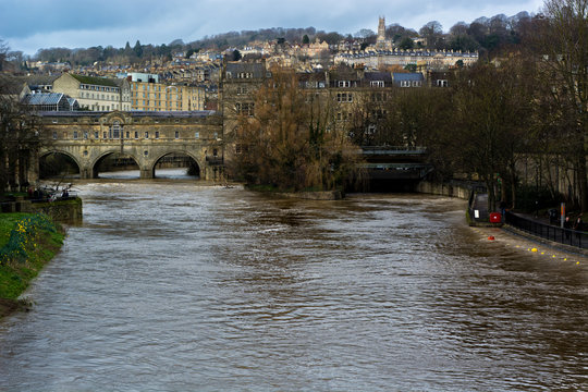 River Avon through Bath at very high level. River is at its limit, causing the Radial Gate to be raised to prevent flooding.  The horseshoe wier by Pulteney Bridge is barely visible.
