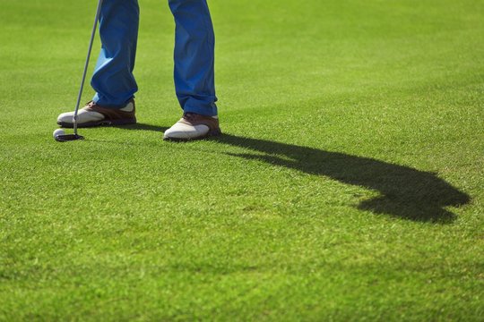 A golf player is preparing for his putting shot on a green - Powered by Adobe