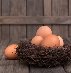 Brown Eggs in a Nest on a Rustic Wooden Surface and Background