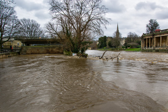 River Avon through Bath at very high level. River is at its limit, causing the Radial Gate to be raised to prevent flooding.  The horseshoe wier by Pulteney Bridge is barely visible.
