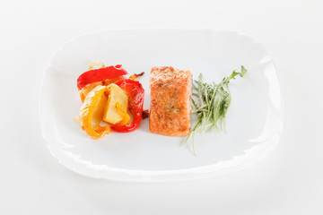 Grilled salmon fillet with vegetables, spices and arugula on a plate