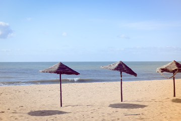 Exotic beach with palm tree umbrellas, golden sand, azure water