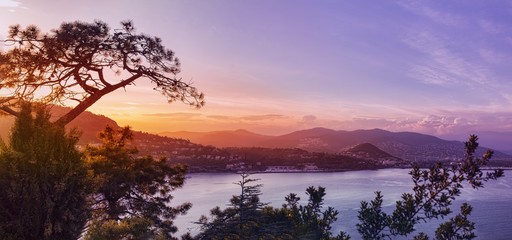 Panoramic view over a coastal town at sunset - obrazy, fototapety, plakaty