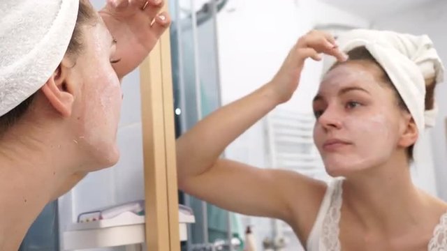 Woman applying mask cream on face in bathroom 4K