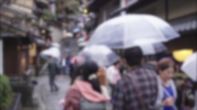 Tourists walking in the street with umbrella raining in Kyoto, Japan , defocused for background usage