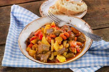 Beef stew with vegetables on a rustic wooden table.