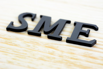 SME (or Small and Medium Enterprises) sign on wood background