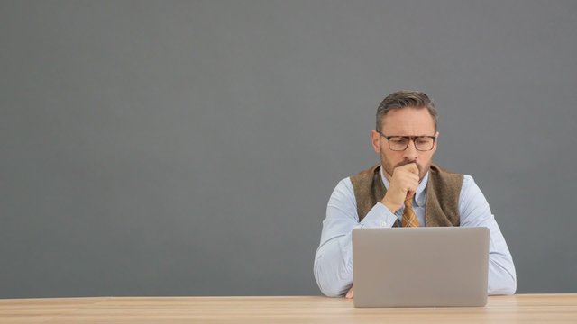Man sitting in front of laptop with thoughtful expression