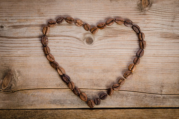 Frame- heart from coffee beans on  wooden table
