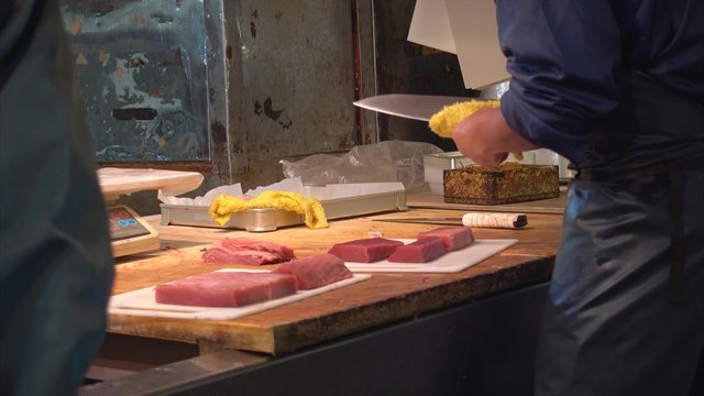 fish butcher slicing cut tuna meat in seafood Tsukiji market, Japan
