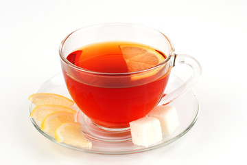 Glass cup with tea and lemon wedges.