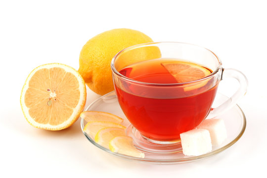 Glass cup of tea near several lemons.