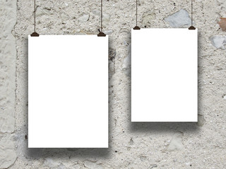 Close-up of two hanged paper sheet frames with clips on old wall background