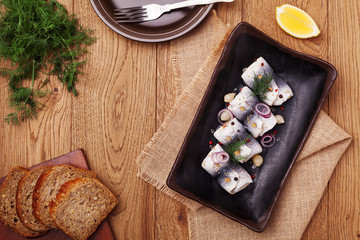 Fototapeta na wymiar Rolled herring in vinegar, served with onions and pickles.