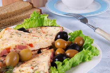 Omelet slices on lettuce leaves and several olives