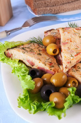 Several omelet slices on lettuce leaves and olives