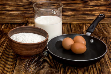Fototapeta na wymiar Frying pan and ingredients for a batch of pancakes - milk, eggs,