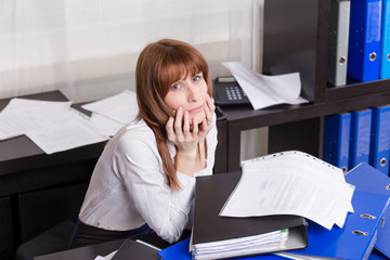 Overworked businesswoman with folders.