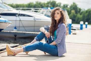 Fototapeta na wymiar Young beautiful woman relaxing on the dock near the boat on a sunny day