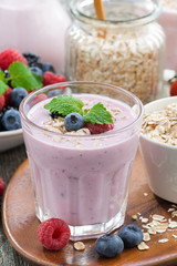 berry smoothie with oatmeal in a glass on wooden table, vertical