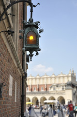In the foreground a little ornamental streetlight, in the background (out of focus), the main Market Square located in the city of Krakow in Poland