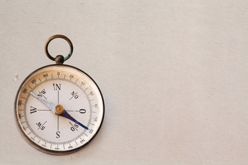 Ancient magnetic exploration compass on vintage paper background, copy space
