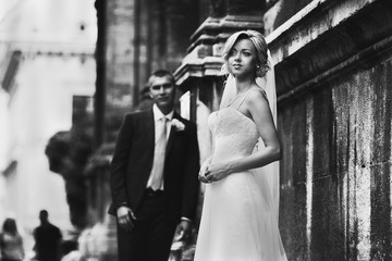 Obraz premium Bride and groom posing near old baroque church b&w