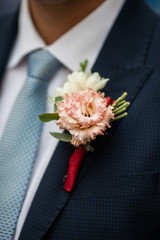 Elegant stylish groom in black suit with fresh flower boutonnier