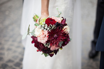 Stylish bride in vintage white dress posing with wedding bouquet