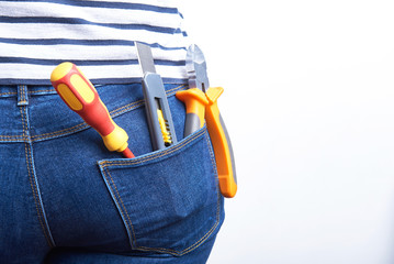 Tools for electrician in back pocket of blue jeans worn by a woman. Screwdriver, sharp knife and...
