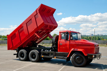 Red dump truck with the body lifted for unloading.