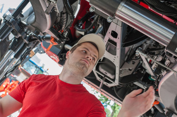 Young repairman ( farmer )  repairs tractor