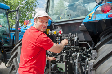 Young repairman ( farmer )  repairs tractor