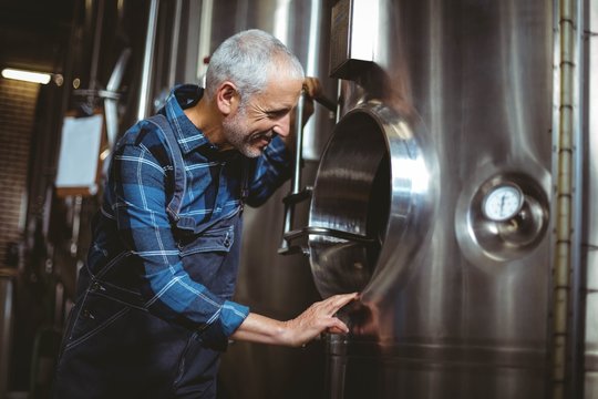 Happy brewer checking large vats