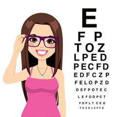 Beautiful young girl with glasses reading sight test characters at ophthalmologist