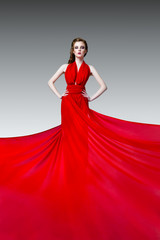 Fashion photo of young magnificent woman in red long dress, studio photo