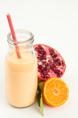 Healthy orange, pomegranate and kefir yogurt smoothie milkshake. Served with fresh sliced orange and whole pomegranate. Isolated on white background.