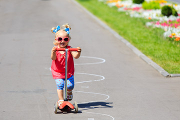 cute little toddler girl riding scooter in the city