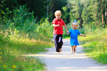 Fototapeta premium little boy and toddler girl running in summer forest