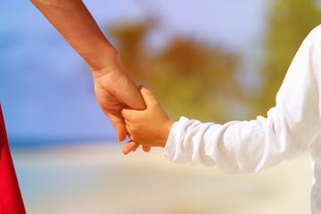 mother and son holding hands on beach