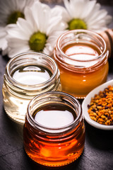 Honey in jar with honey dipper on black stone background