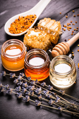 Honey in jar with honey dipper on black stone background