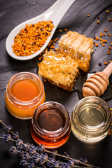 Honey in jar with honey dipper on black stone background
