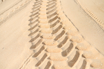 Fototapeta na wymiar Tyre traces on dry sand background for articles about traveling