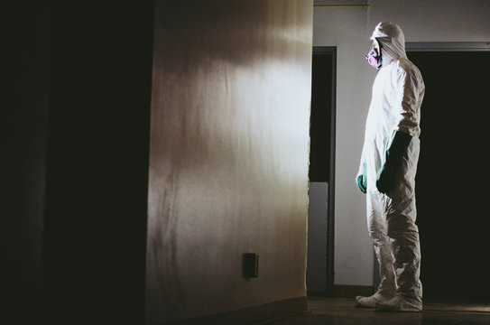 Man wearing a hazardous material protective clean suit, facing bright light in hallway