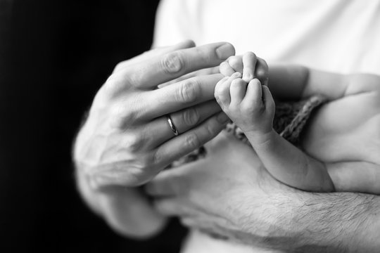 Newborn children's hand in father hand. Black-and-white photo.