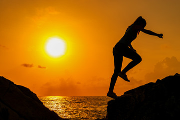 Girl runs along the cliffs by the sea at dawn