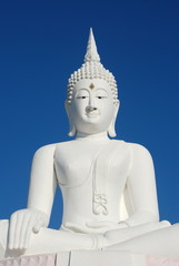 Fototapeta na wymiar Big white buddha statue on blue sky at Pasak Jolasid Dam, Thailand