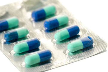 Small round blue and green pills in blister pack isolated on whi